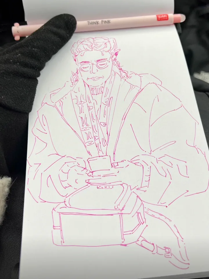 Pink-ink line sketch of a passenger with a curly mullet and round glasses, hands resting on a bag in their lap. A gloved hand holds the pad, with the pink pen resting along its top edge.